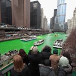 Chicago River dyed bright green for St Patrick’s Day with crowds watching boats in the city centre