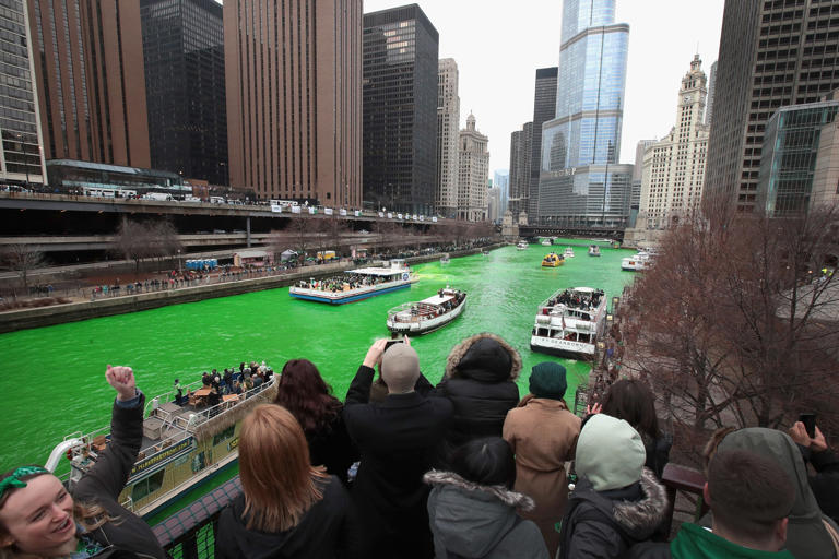 Chicago River dyed bright green for St Patrick’s Day with crowds watching boats in the city centre